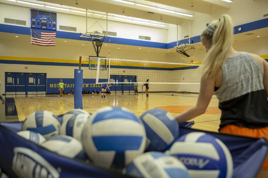 Volleyball player scooping up a ball in practice.